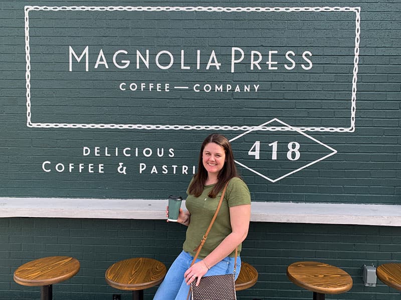 Barbara outside of Magnolia Press in Waco, TX with a cup of Texas Pecan coffee